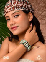 Shuktimālā- Shell band-Expandable bracelet crafted from shell beads, combining turquoise and beige-brown tones with a brassy finish.