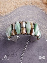 Shuktimālā- Shell band-Expandable bracelet crafted from shell beads, combining turquoise and beige-brown tones with a brassy finish.