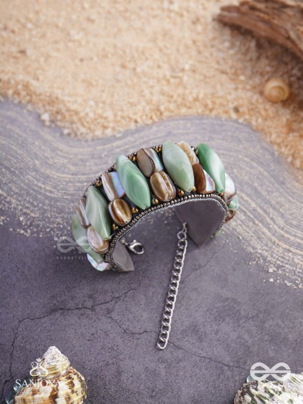 Shuktimālā- Shell band-Expandable bracelet crafted from shell beads, combining turquoise and beige-brown tones with a brassy finish.