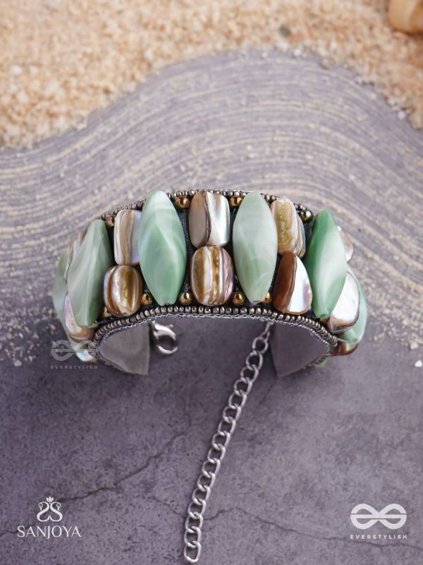 Shuktimālā- Shell band-Expandable bracelet crafted from shell beads, combining turquoise and beige-brown tones with a brassy finish.