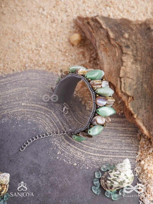 Shuktimālā- Shell band-Expandable bracelet crafted from shell beads, combining turquoise and beige-brown tones with a brassy finish.