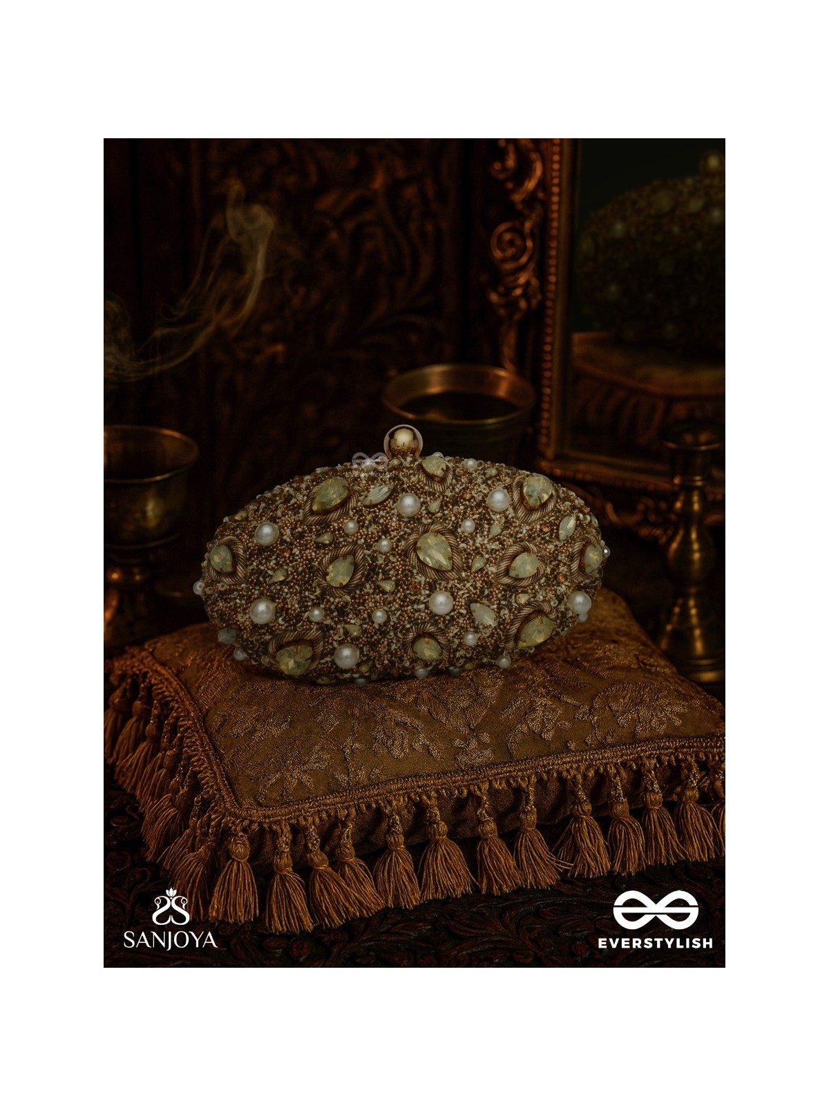CHANDRAAYA – POLISHED OVAL GOLDEN BRONZE SILK CLUTCH WITH INTRICATE JEWEL STONE EMBELLISHMENT AND GOLDEN METAL FRAME