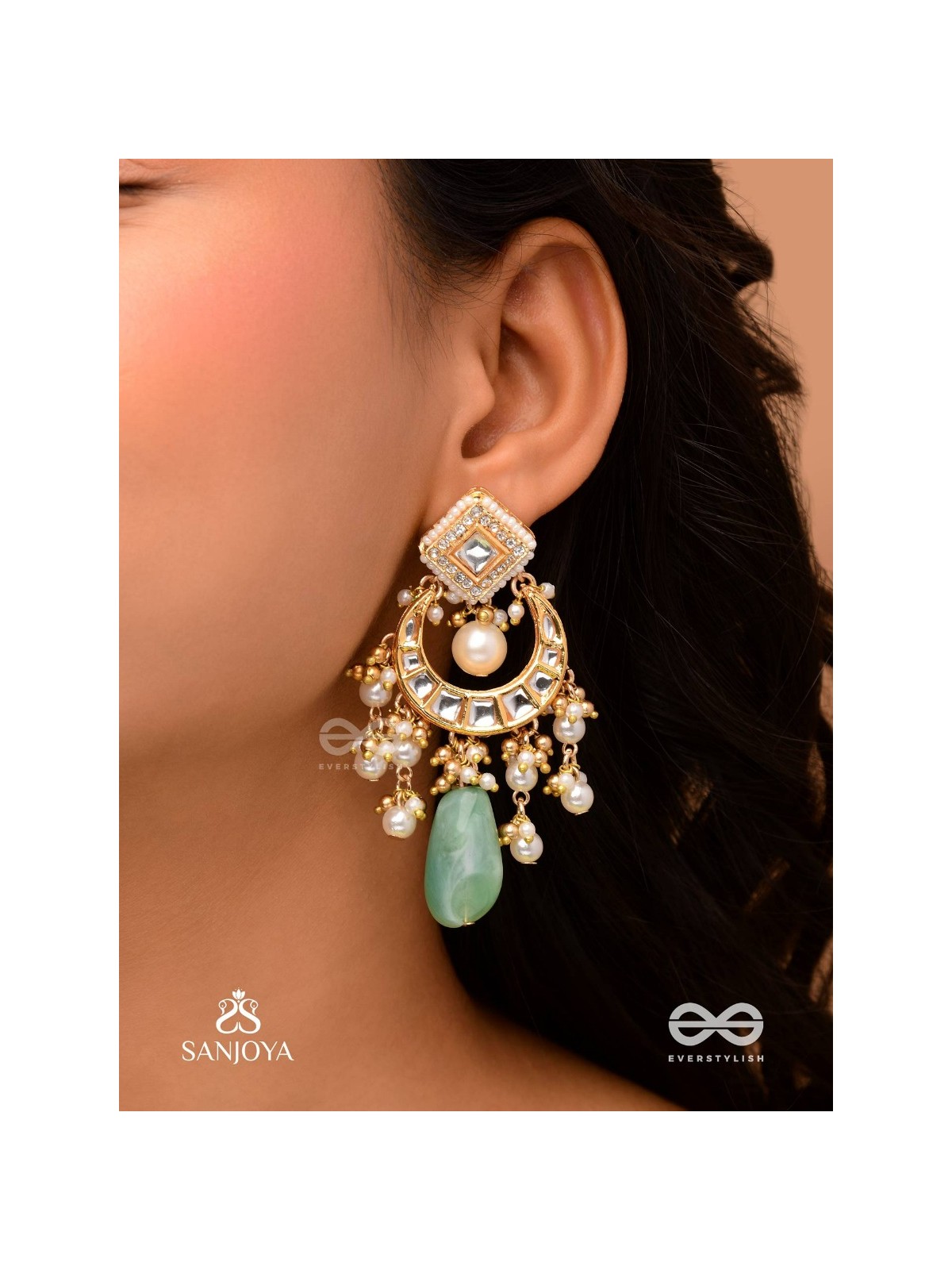 PURNIMA PHOOL – FULL MOON FLOWER AN EXQUISITE KUNDAN EARRING FEATURING GOLDEN DESIGNS, PEARL CLUSTERS, AND A GREEN GEMSTONE DROP, SYMBOLIZING ELEGANCE